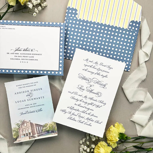 Wedding invitation set with blue and white patterned envelope, card, and matching Save the Date card on a gray surface with yellow flowers.