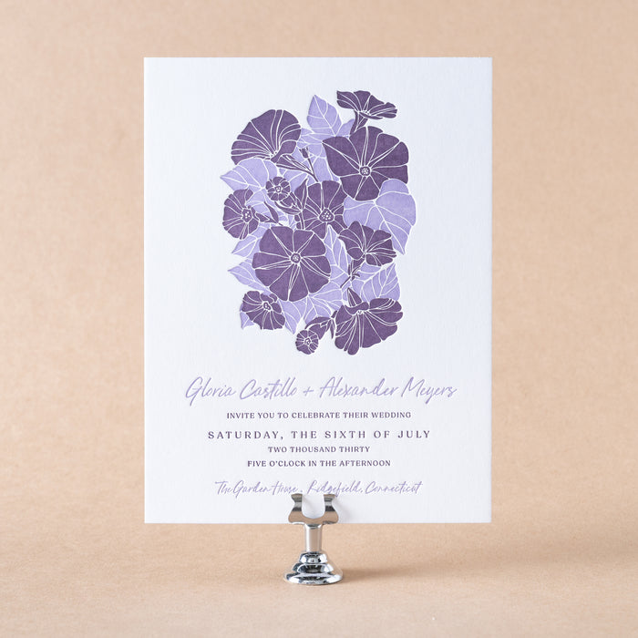 Gloria Wedding invitation with purple floral design on a beige background