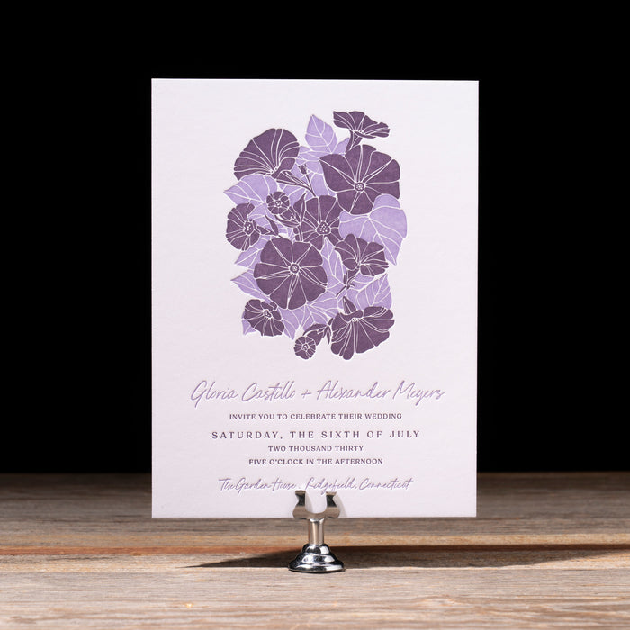 Gloria Floral invitation card on a stand with a black background