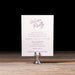 Gloria suite Welcome party invitation card on a stand with a dark background