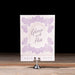 Gloria Save the date card with floral design and text on a stand against a black background