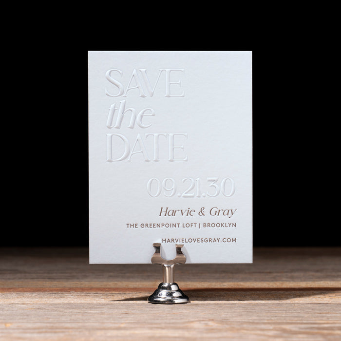 Sky blue 'Save the Date' card on a stand with a black background