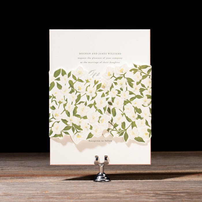 Ashby Wedding Invitation card with green floral pattern wrap on a wooden surface with black background