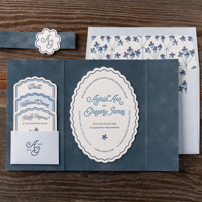 Astrid wedding invitation set with navy blue and white design on a wooden surface