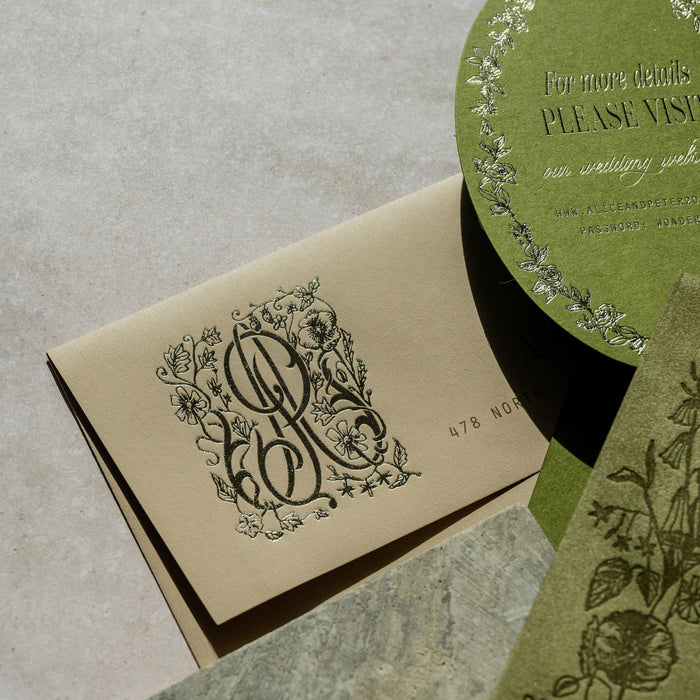 Decorative stationery items including a card with a monogram and a round green card on a textured surface.