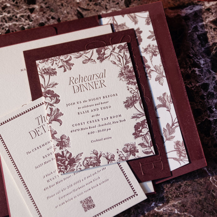 Floral invitation card for a rehearsal dinner on a textured surface