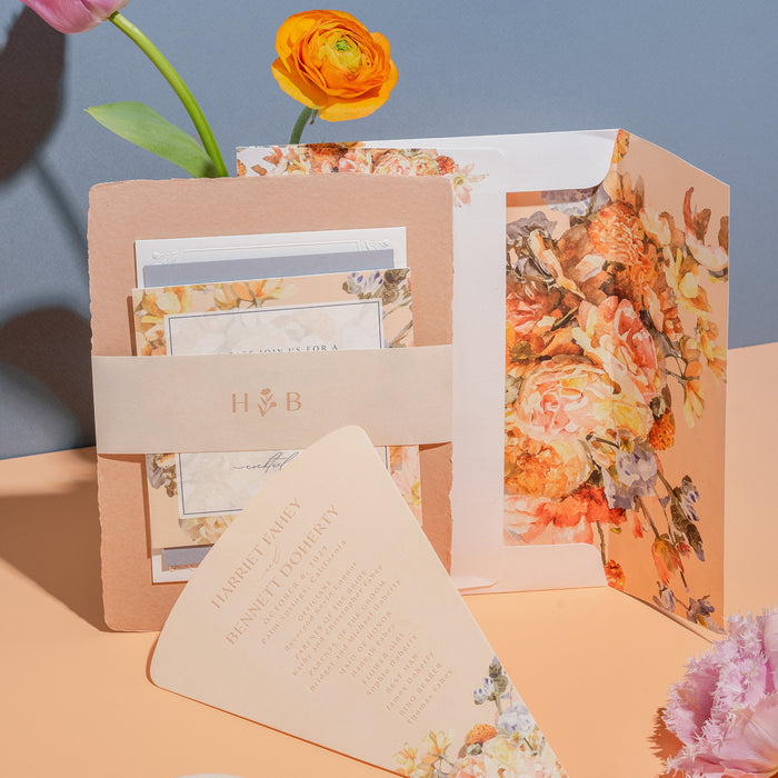 Floral  Harriet invitation set with pink ribbon on a peach surface and blue background