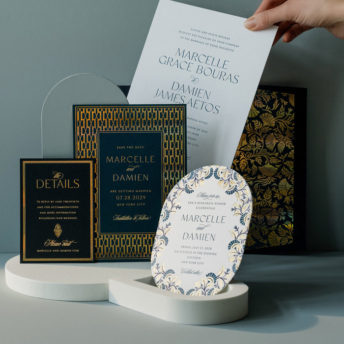 Collection of wedding invitation cards from Marcelle suite on a stand with a hand holding a card against a neutral background