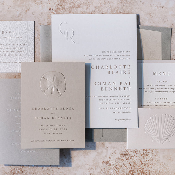 Set of elegant wedding invitations from Sedna Suite with shell designs on a textured surface