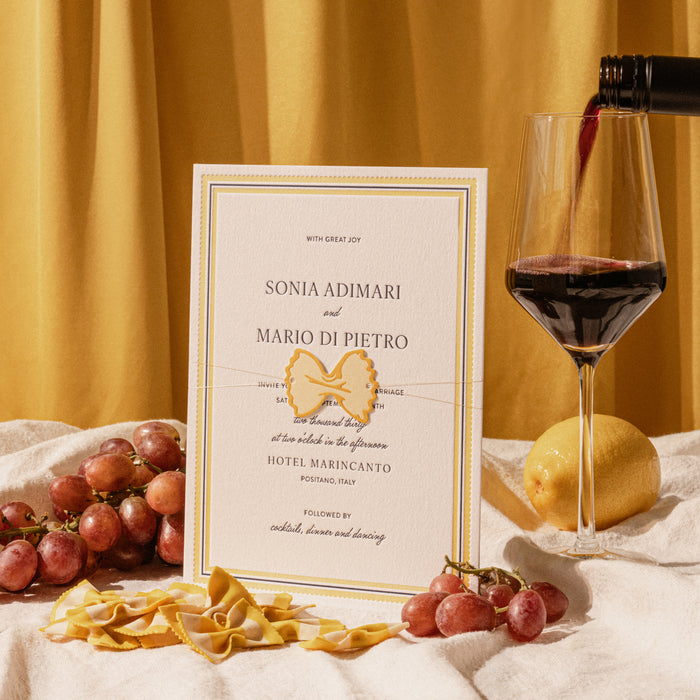 Italo wedding invitation card with red wine, grapes, and pasta on a yellow background