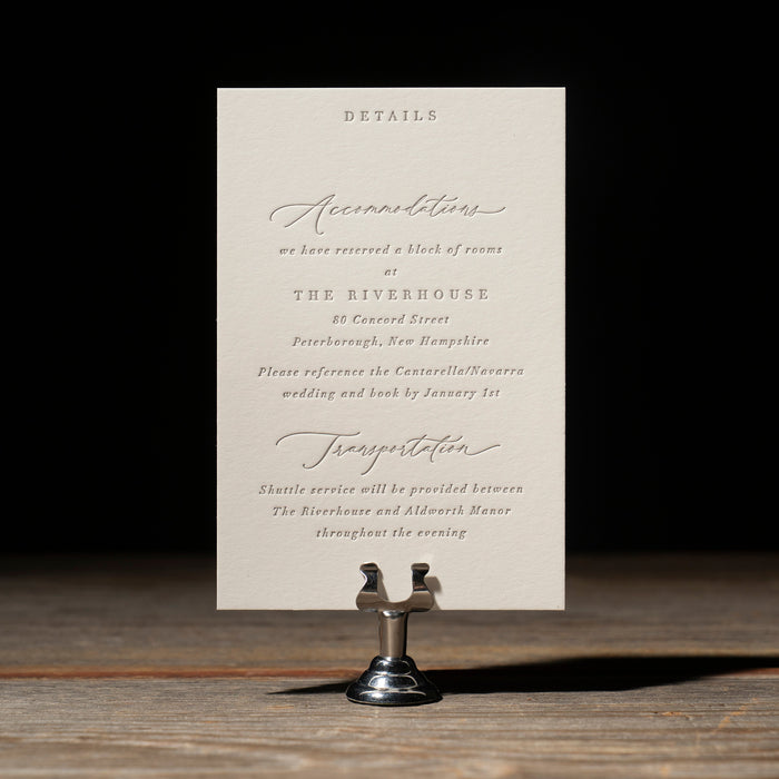 Wedding invitation details card on a stand with a dark background