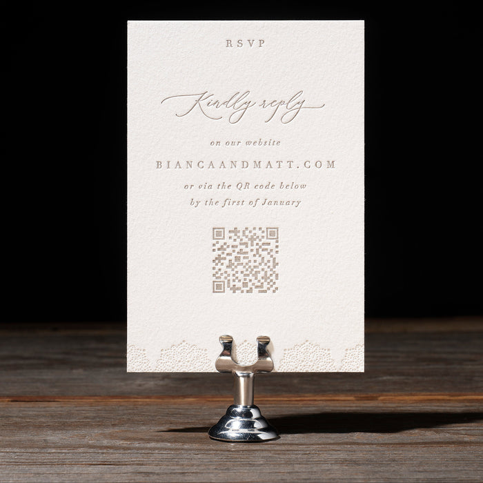 Bianca RSVP card with text and QR code on a dark wooden surface