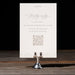 Bianca RSVP card with text and QR code on a dark wooden surface