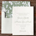 Braxton v2 wedding invitation card with green floral liner on a wooden surface