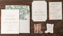 Wedding invitation set with floral design and cowboy boot on a wood background