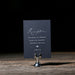 Navy blue reception card on a stand with a dark background