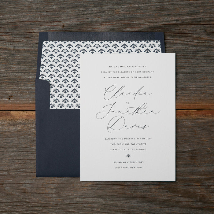 Wedding invitation card with blue and white patterned envelope on a wooden surface
