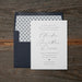 Wedding invitation card with blue and white patterned envelope on a wooden surface