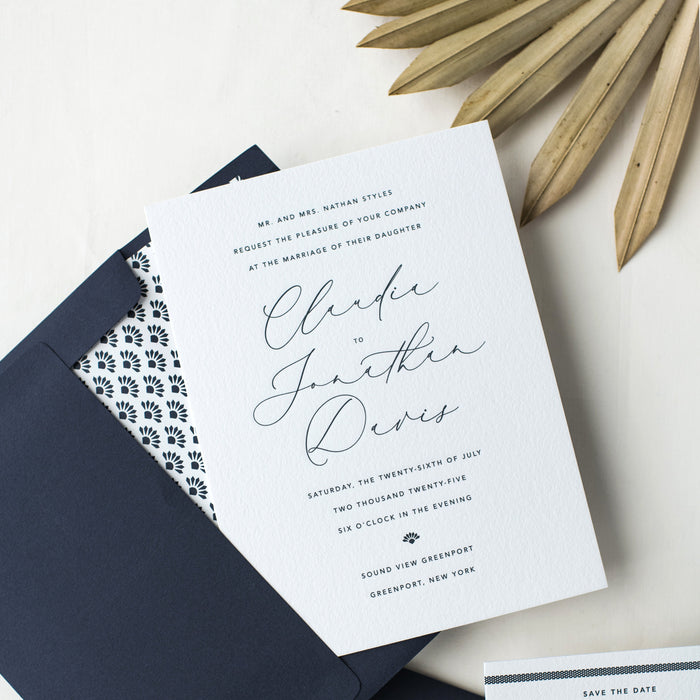 Wedding invitation card with navy envelope and decorative elements on a light background