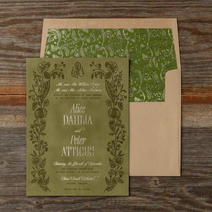 Green Darcy wedding invitation with floral design on a wooden surface