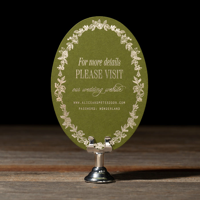 Green oval card with foil text and decorative elements on a wooden surface