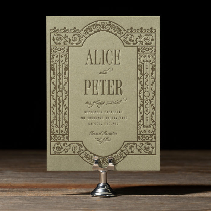 Darcy Save the Date with ironwork like detailing on a stand with a dark background