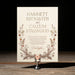 Devonshire wedding invitation card with floral design on a stand against a dark background