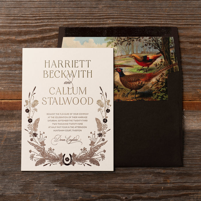 Devonshire Wedding invitation with pheasant illustration on a wooden surface