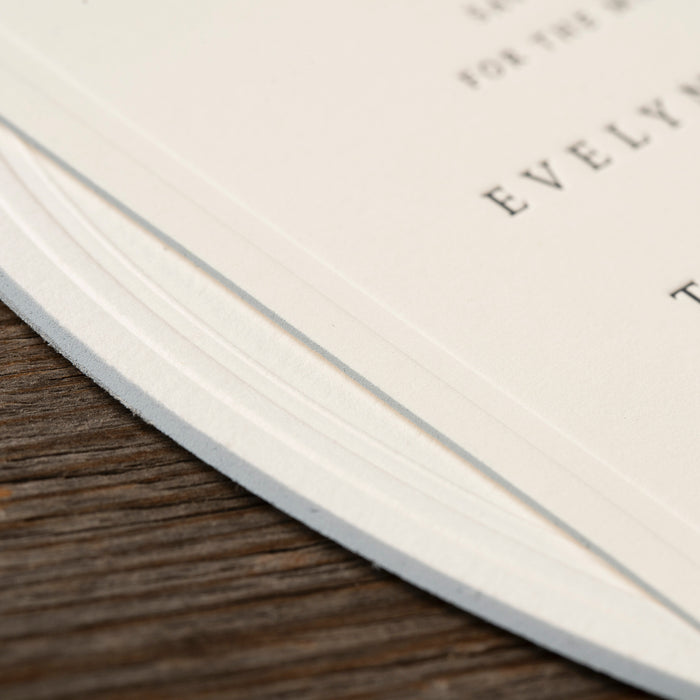 Close-up of a wedding invitation card with edge detail on a wooden background.