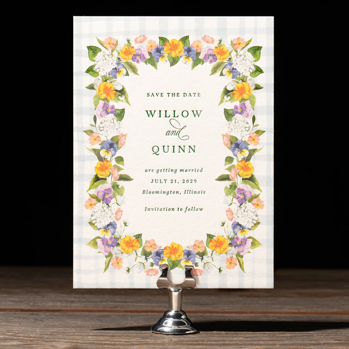 Floral save the date card on a stand with a dark background