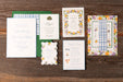 Collection of floral and checkered stationery items on a wooden surface