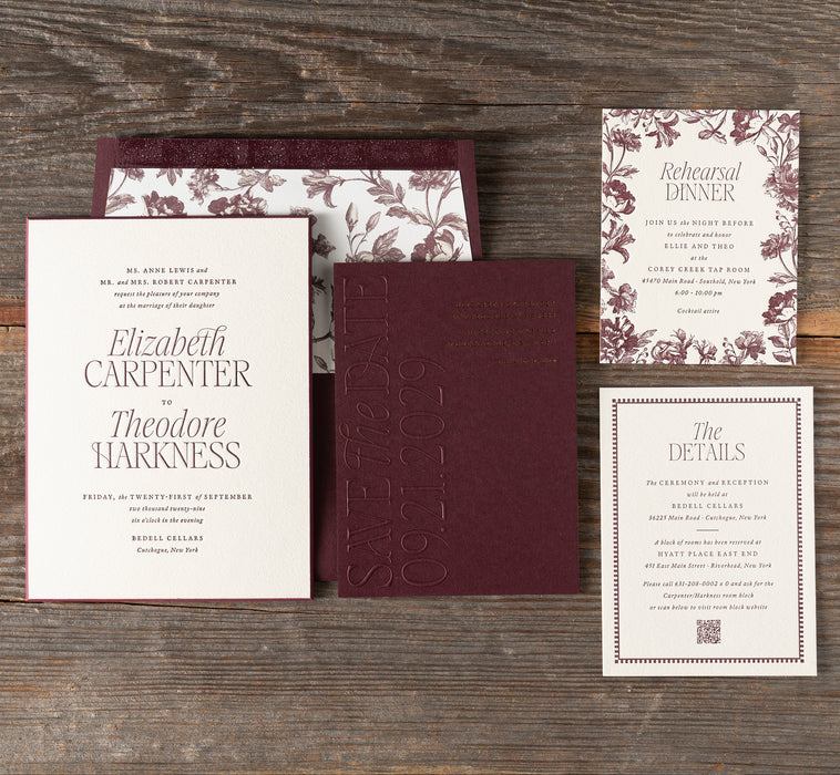 Harkness wedding invitation set with burgundy and floral design on a wooden surface