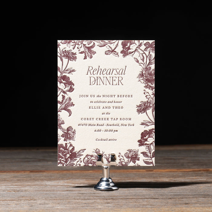 Harkness rehearsal dinner invitation with floral design on a wooden surface