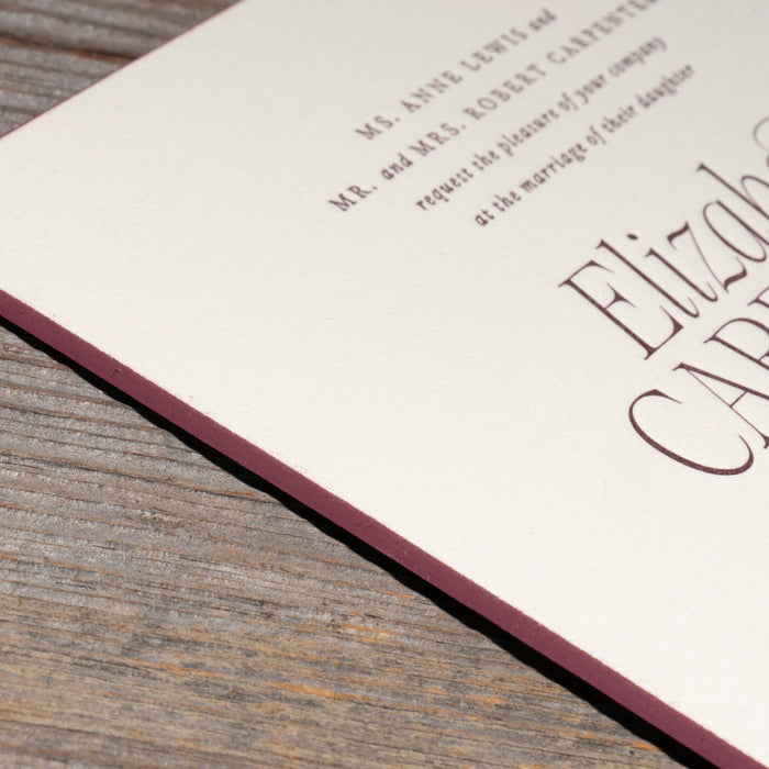 Invitation card edge detail with text on a wooden surface