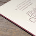 Invitation card edge detail with text on a wooden surface