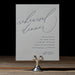 Gray blue rehearsal dinner invitation card on a stand with a black background