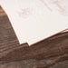 White paper with engraved text and rose gold edgepaint on a wooden surface