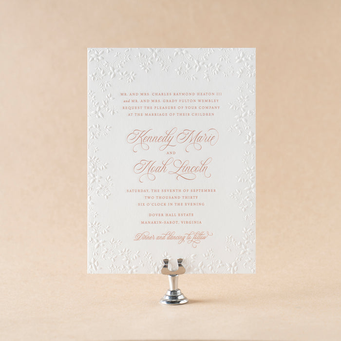 Elegant Heaton wedding invitation card on a beige background with a candle holder.