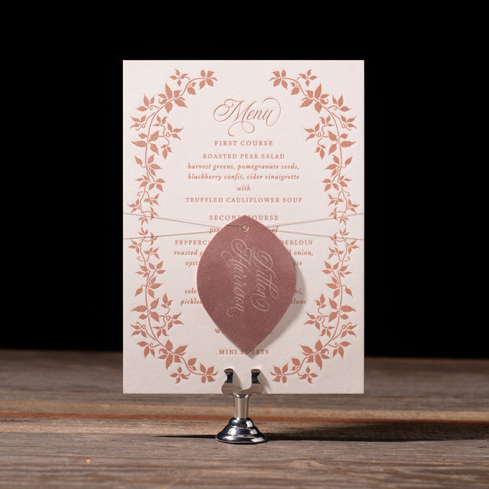 Heaton decorative menu card with floral design on a stand against a dark background