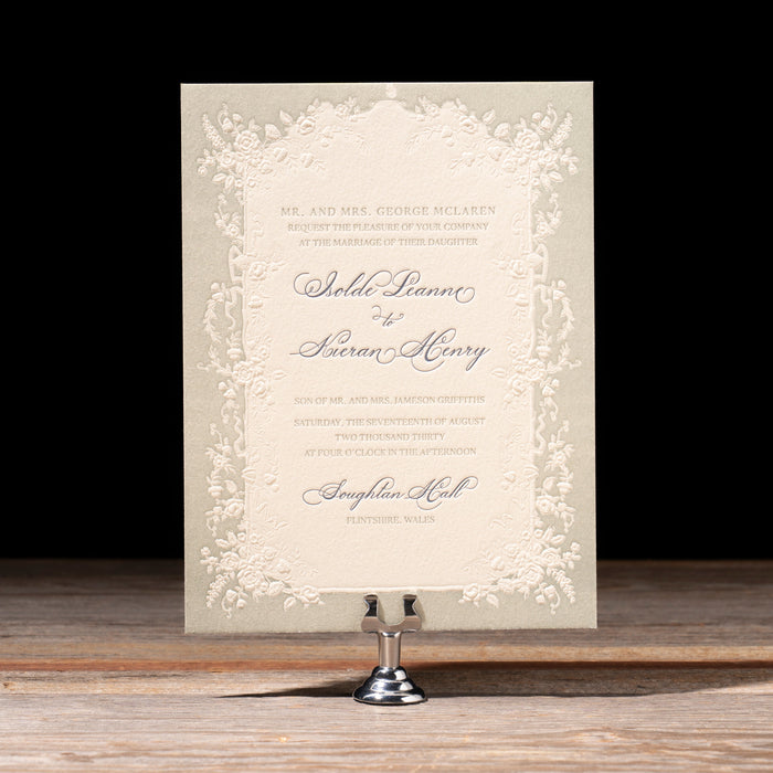 Decorative Isolde wedding invitation card on a stand with a black background