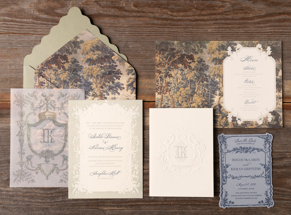 Collection of vintage-style wedding invitation pieces from Isolde Suite on a wooden surface