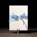 Lainey wedding invitation card with a blue ribbon on a dark background