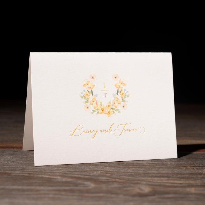 Thank you card with gold floral design and text on a wooden surface