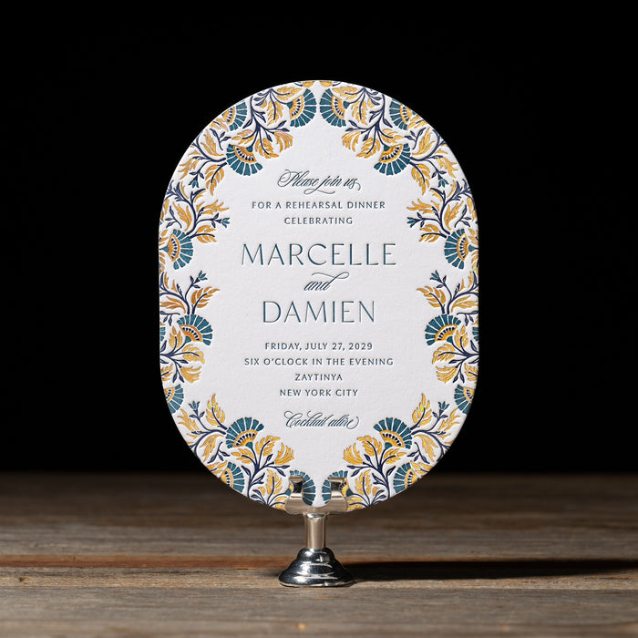 Decorative Marcelle Rehearsal Dinner invitation on a stand with floral patterns