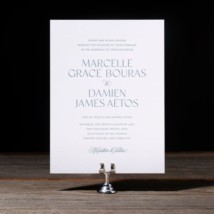 Marcelle Wedding Invitation card on stand on dark background.