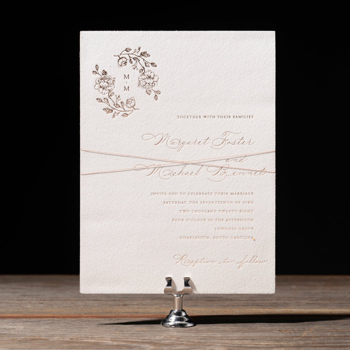 Invitation card with floral design and text on a stand against a dark background