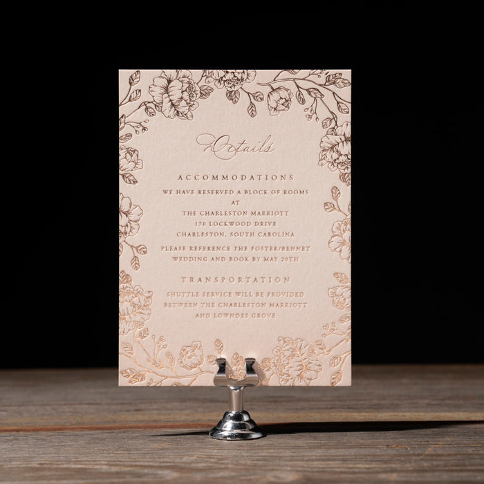 Wedding invitation card with floral design on a stand against a dark background