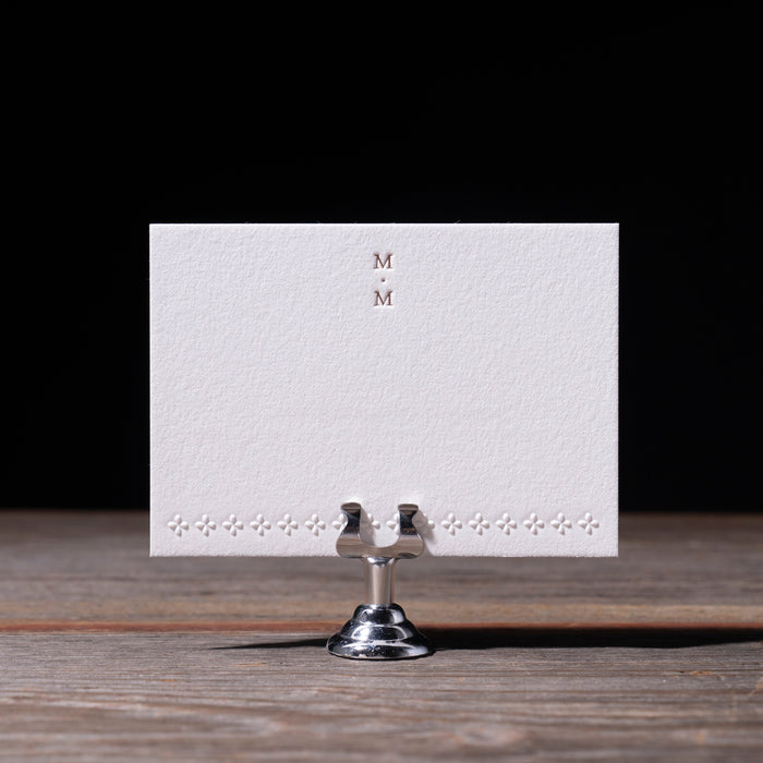 White card with 'MM' on a stand against a dark background