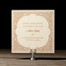 Decorative Nash 'Save the Date' card with intricate patterns on a wooden stand against a black background.