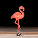 Pink flamingo-shaped website card on a wooden surface with a dark background